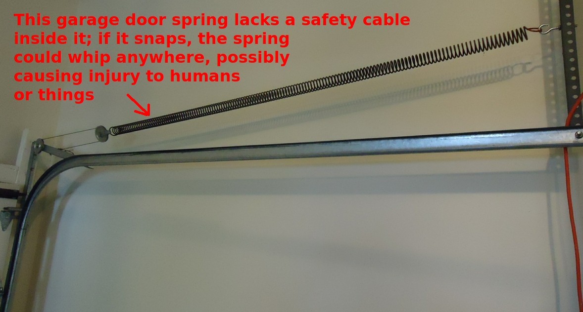Garage door extension spring above the track with an annotation identifying a missing safety cable